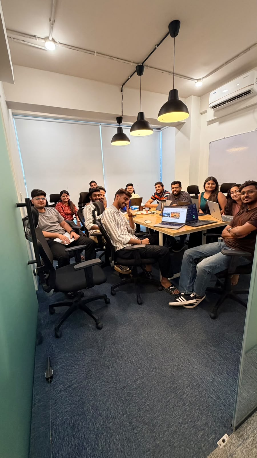 Trivas team huddled around a meeting room table, shot one